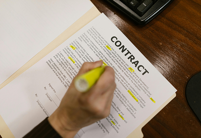 A lawyer's hand highlighting a contract