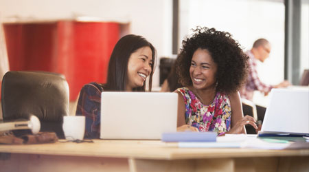 two friends chatting privately at an office