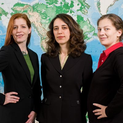 three women in black suits in front of a map